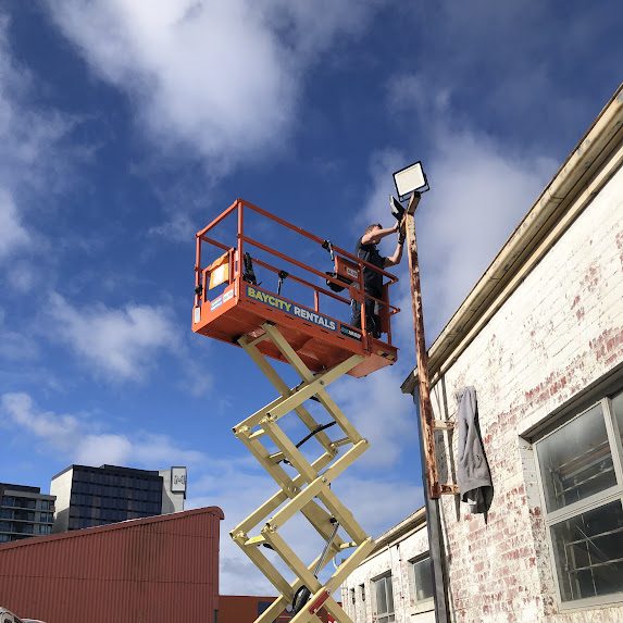 Commercial floodlight installation from scissor lift — S+ Electrical Services Melbourne